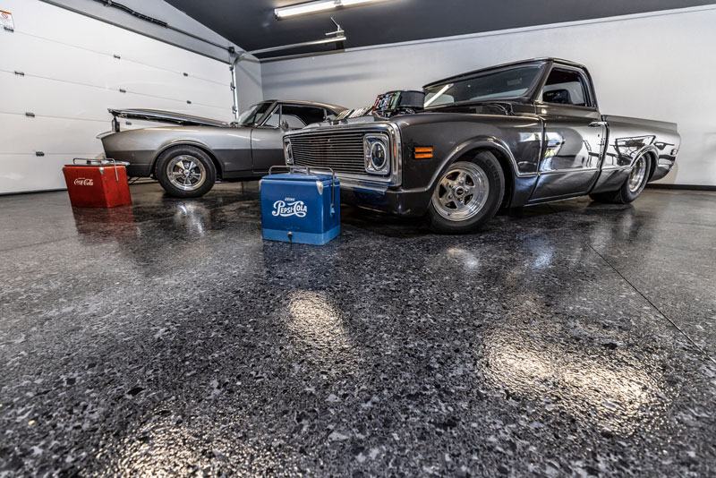 High-gloss flake garage floor under two classic trucks